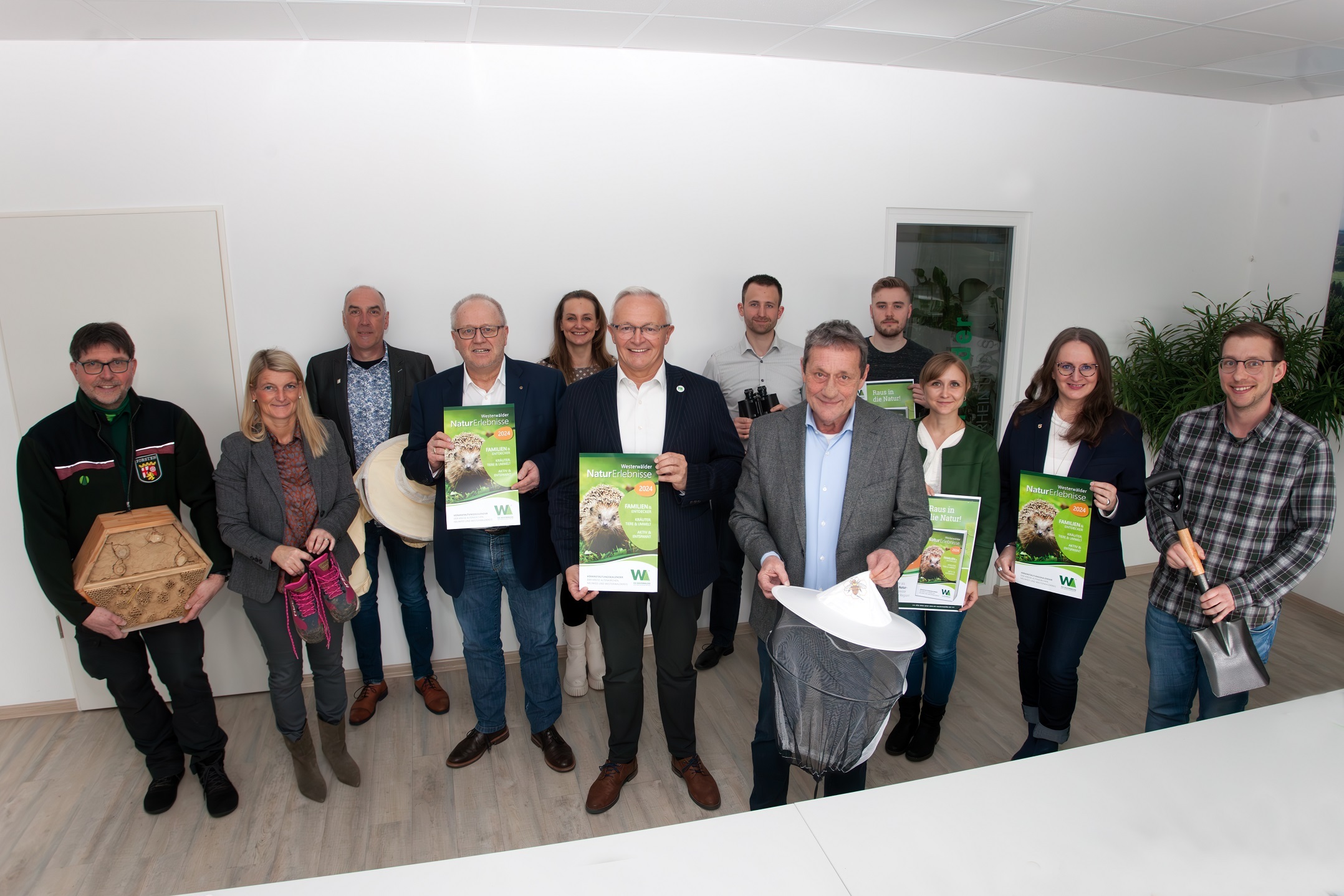 Frauen und Männer halten Plakate und Utensilien wie Spaten und Imkerhut in der Hand.
