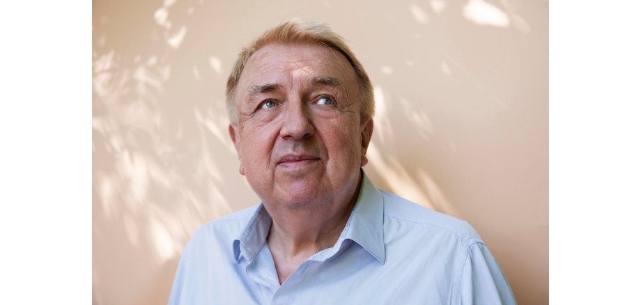 Ein Mann im Porträt mit blauem Hemd.