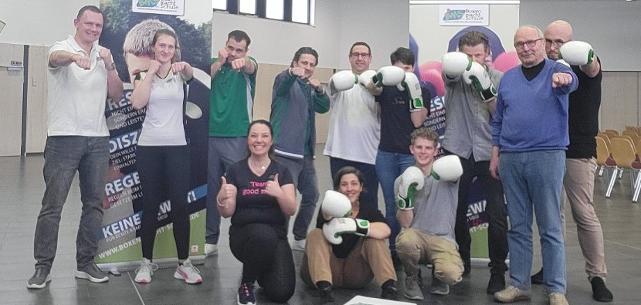 Eine Gruppe aus zwölf Personen trägt weiße Boxhandschuhe und posiert passend zum Thema "Ring frei".