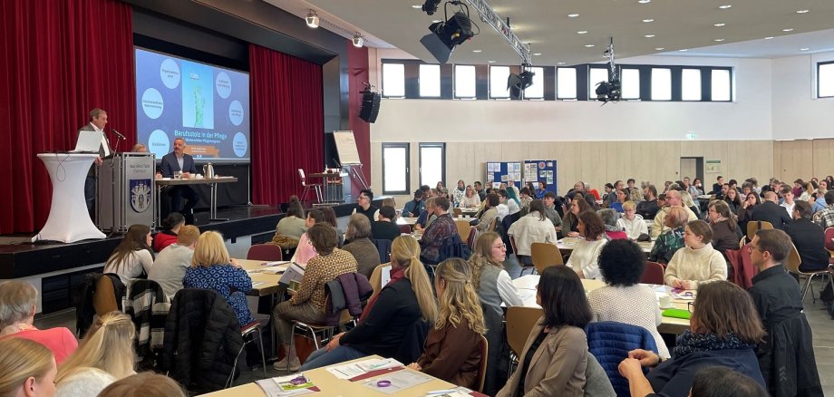 Zahlreiche Personen haben sich im Bürgerhaus in Wirges eingefunden und verfolgen an Gruppentischen die Vorträge während der Kreispflegekonferenz.