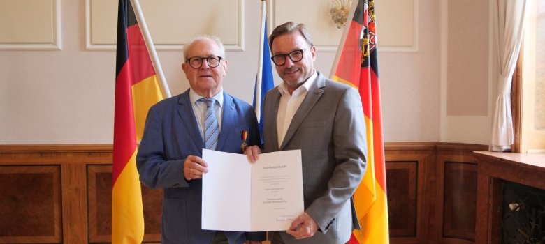 Artur Breiden, dem von Wolfgang Treis die Landesverdienstmedaille übergeben wird.