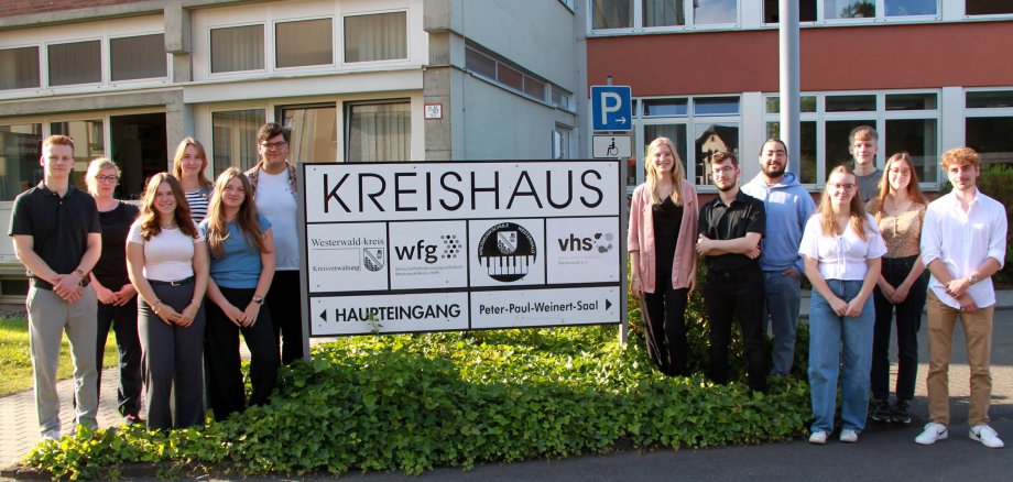 Eine Gruppe Jugendlicher steht um das Eingangsschild der Kreisverwaltung.