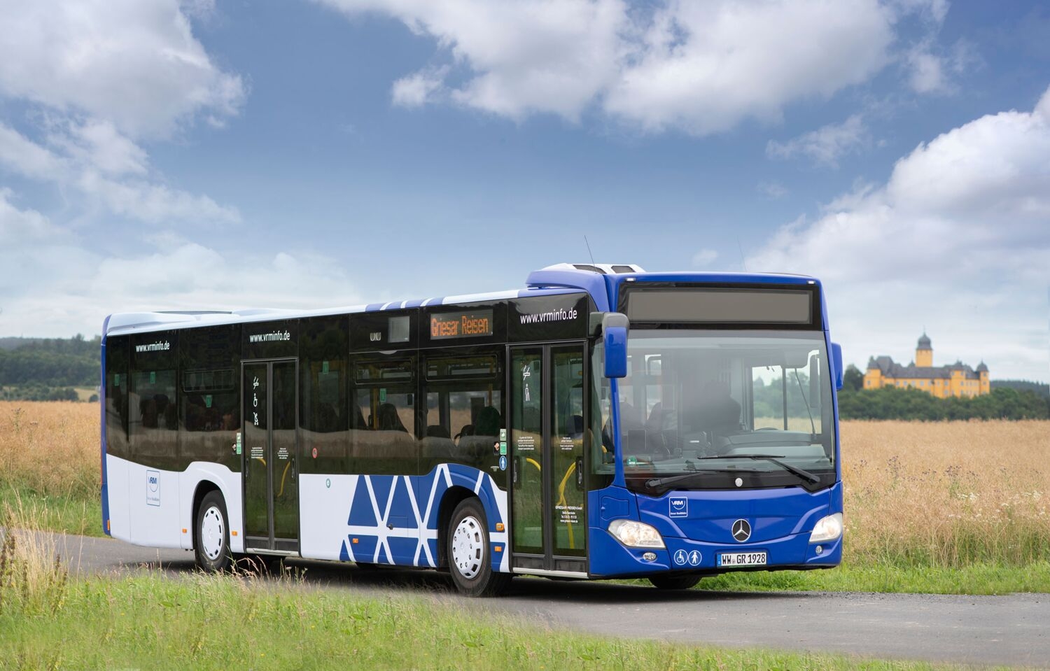 Ein Bus steht vor einem Feld. Im Hintergrund ist das Schloss Montabaur zu sehen.