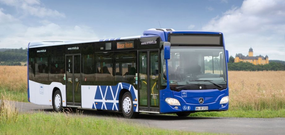 Ein Bus steht vor einem Feld. Im Hintergrund ist das Schloss Montabaur zu sehen.