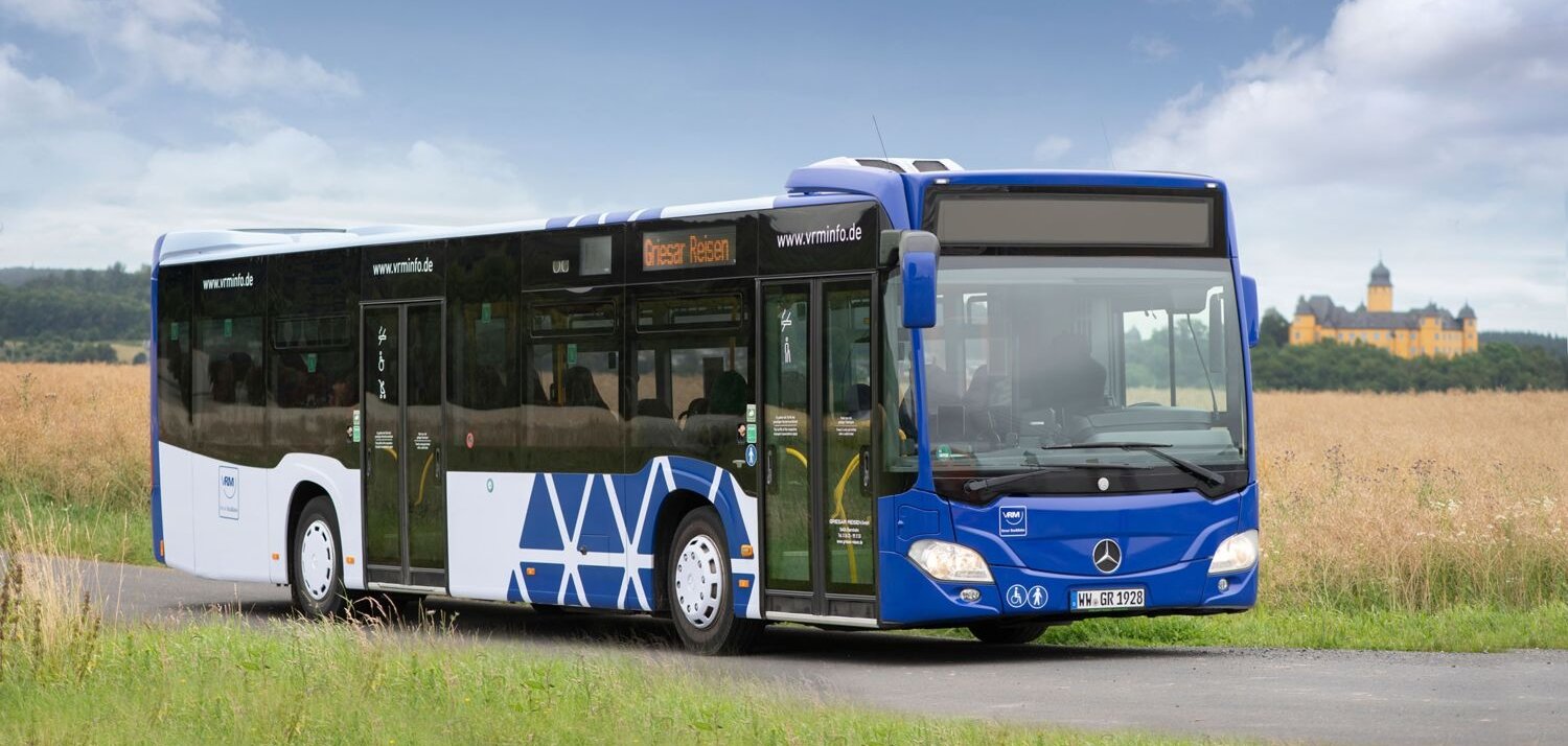 Ein Bus steht vor einem Feld. Im Hintergrund ist das Schloss Montabaur zu sehen.