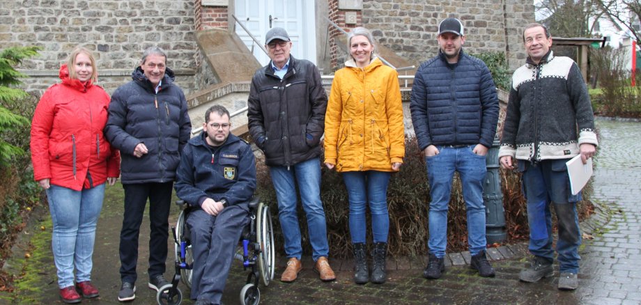 Eine Gruppe von sieben Personen steht im Regen vor der alten Dorfschule in Deesen.