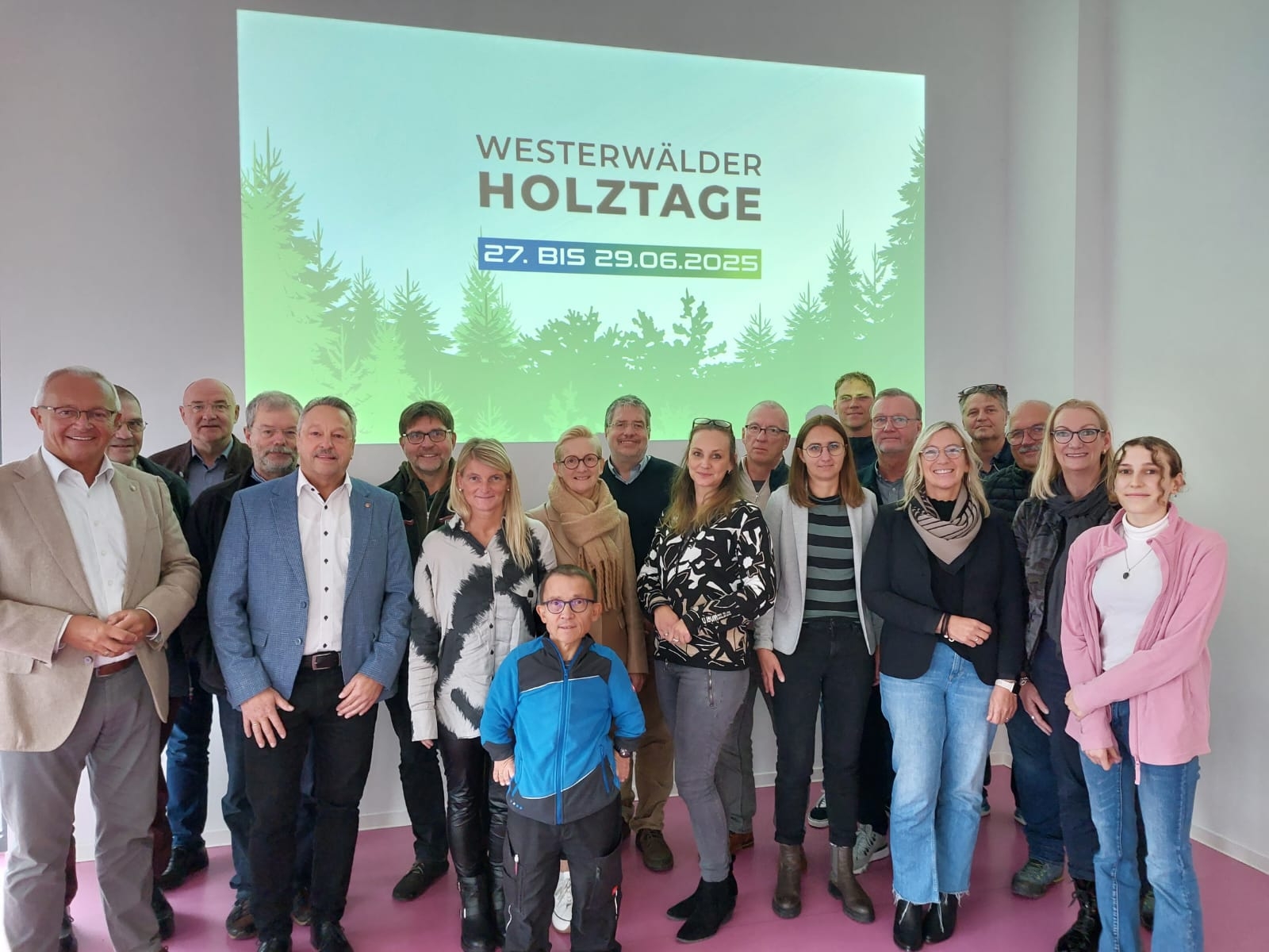 Eine große Gruppe Menschen steht vor einer Präsentationsleinwand der Westerwälder Holztage.