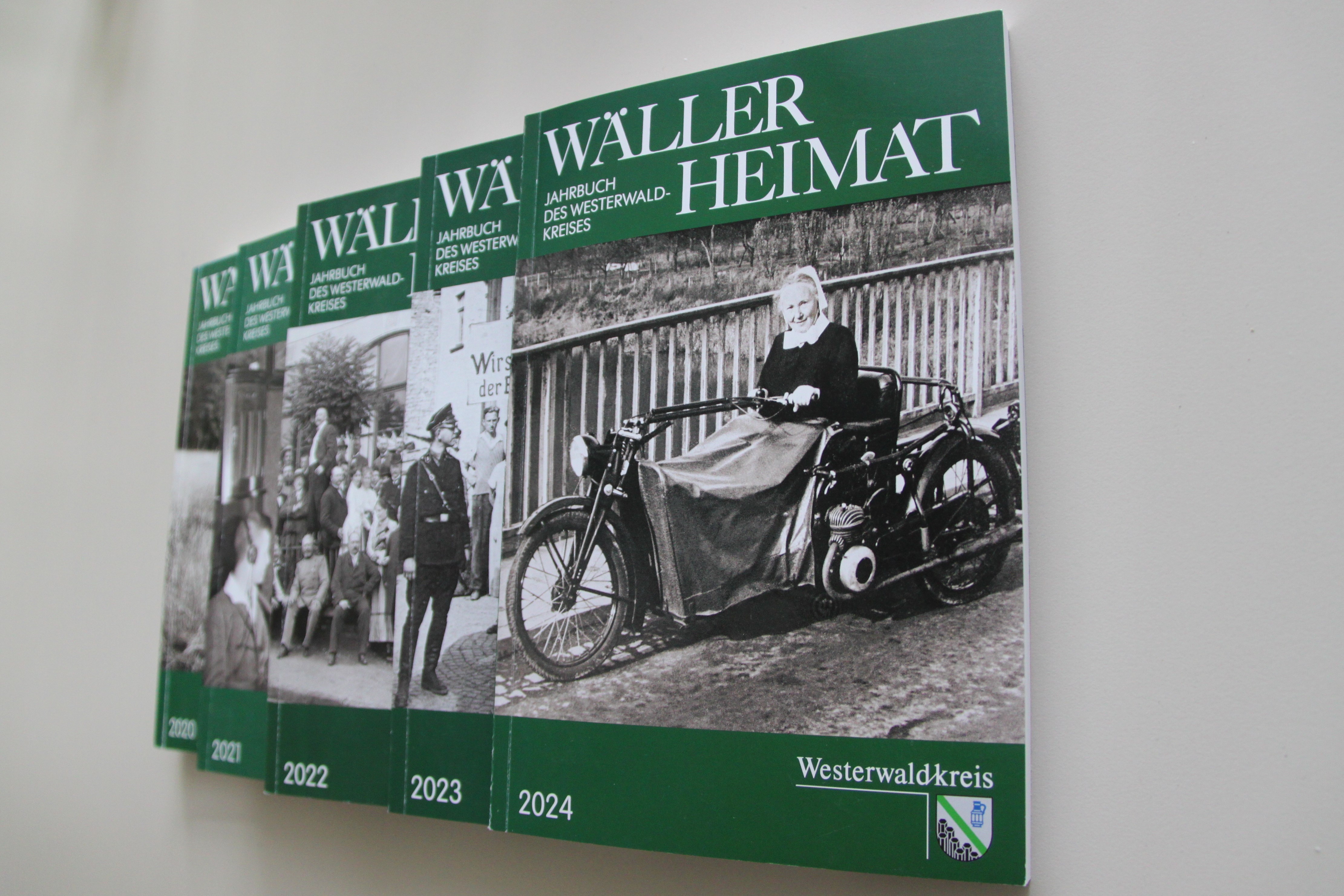 Fünf verschiedene Ausgaben des Heimatjahrbuches liegen auf einem Tisch. Es handelt sich jeweils um grüne Bücher mit einem historischen schwarz-weißen Foto auf dem Deckblatt. 