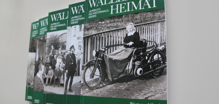 Fünf verschiedene Ausgaben des Heimatjahrbuches liegen auf einem Tisch. Es handelt sich jeweils um grüne Bücher mit einem historischen schwarz-weißen Foto auf dem Deckblatt. 