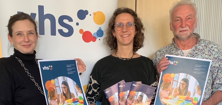Drei Personen präsentieren das neue Kita-Fortbildungsprogramm. Es handelt sich dabei um eine blaue DIN-A5-Broschüre.