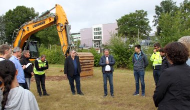 Landrat Achim Schwickert begrüßt die Teilnehmenden, die in einem Kreis auf dem Bauplatz stehen.