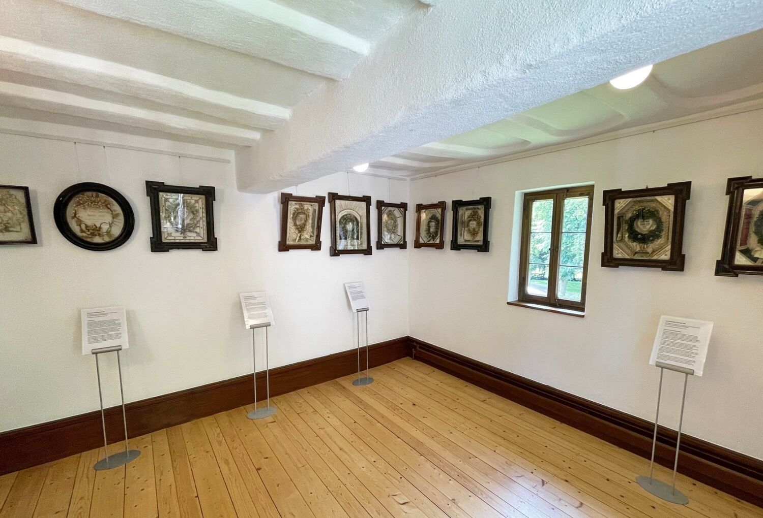 Kastenbilder hängen an der Wand eines Museumsraumes.