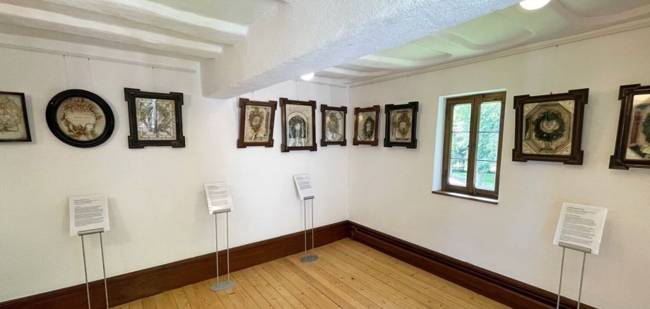 Kastenbilder hängen an der Wand eines Museumsraumes.