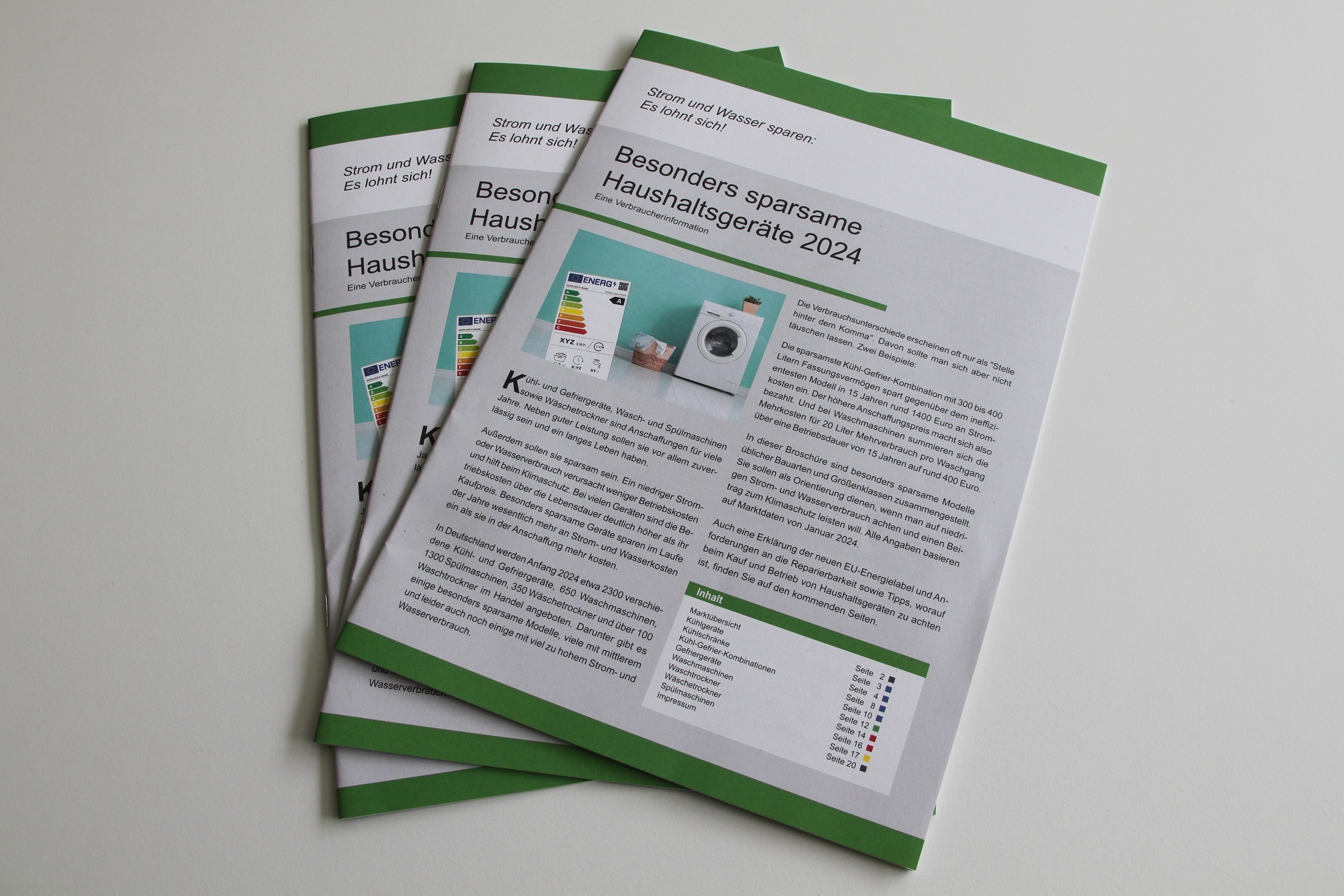Drei Exemplare der Broschüre „Besonders sparsame Haushaltsgeräte 2024“ liegen auf einem Tisch.
