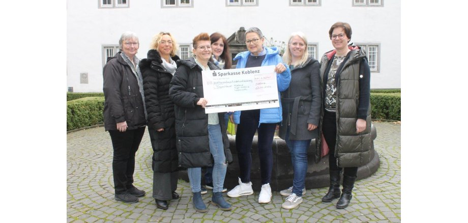 Ein großer Spendenscheck im Wert von 2.220 Euro wird an das Frauenhaus in Koblenz übergeben. 