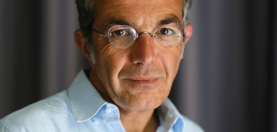 Navid Kermani 2023 Ein Mann mittleren Alters mit Brille und hellblauem Hemd schaut in die Kamera.