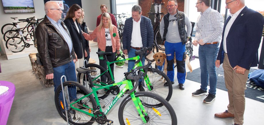 In einem Fahrradgeschäft steht eine Gruppe Menschen um zwei grüne Bikes herum.