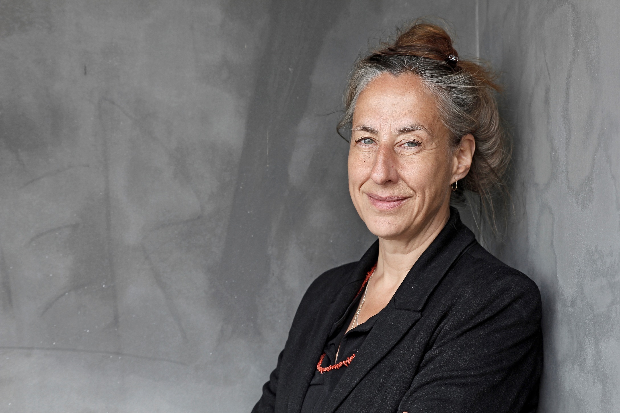 Porträtfoto einer Frau mit hochgesteckten Haaren in einem schwarzen Blazer.
