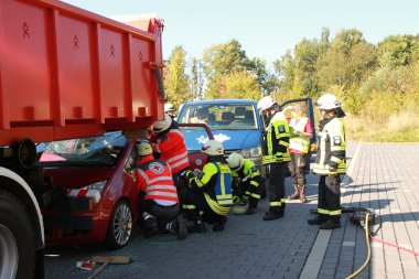 Feuerwehrkräfte schneiden die eingeklemmten Verletzten aus einem Fahrzeug.