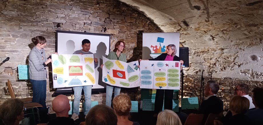 Vier Personen stehen auf der Bühne im Gewölbekeller.