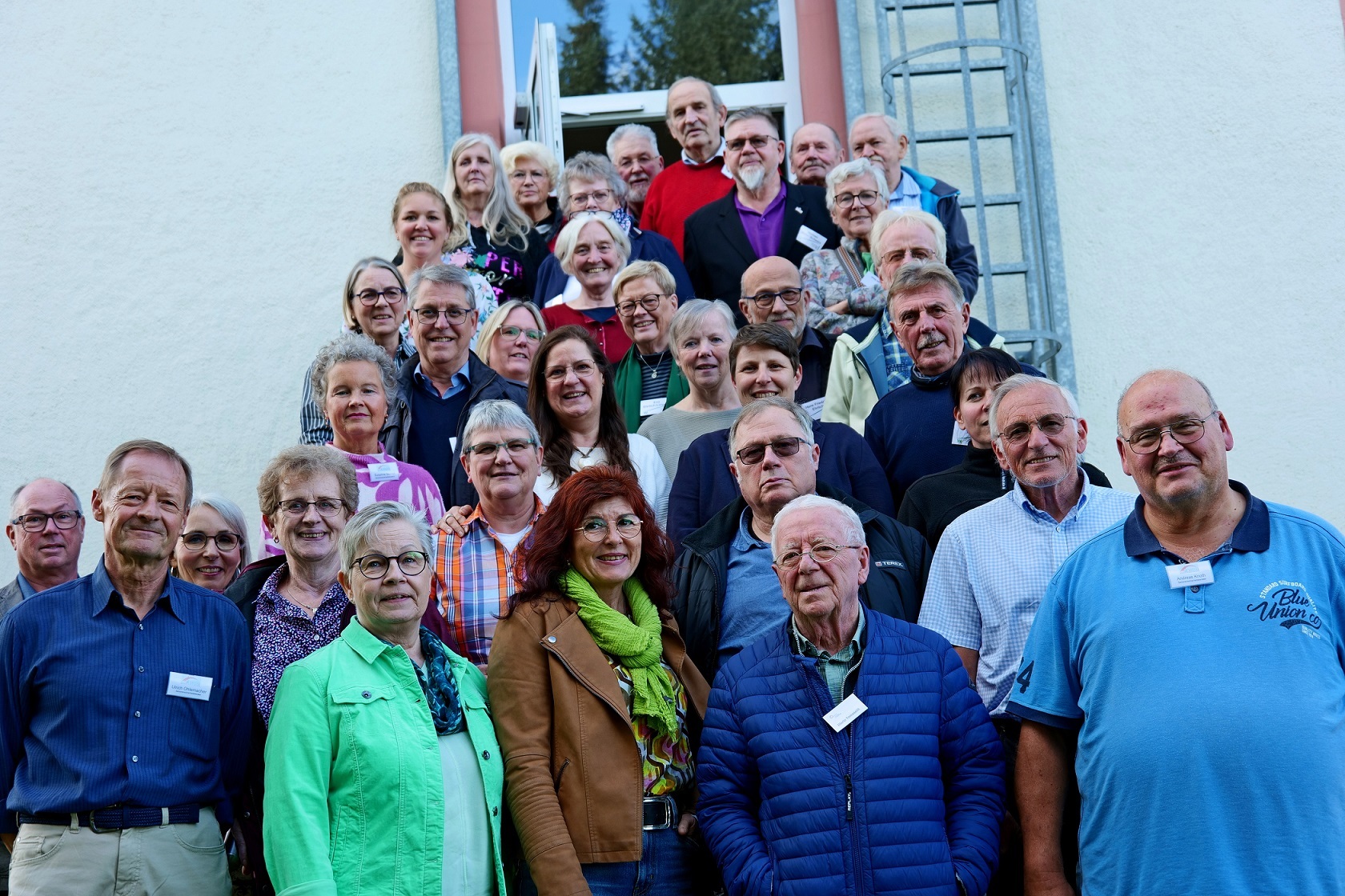 Eine große Gruppe Seniorinnen und Senioren steht vor einem Gebäude auf einer Treppe.