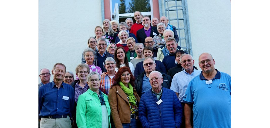 Eine große Gruppe Seniorinnen und Senioren steht vor einem Gebäude auf einer Treppe.
