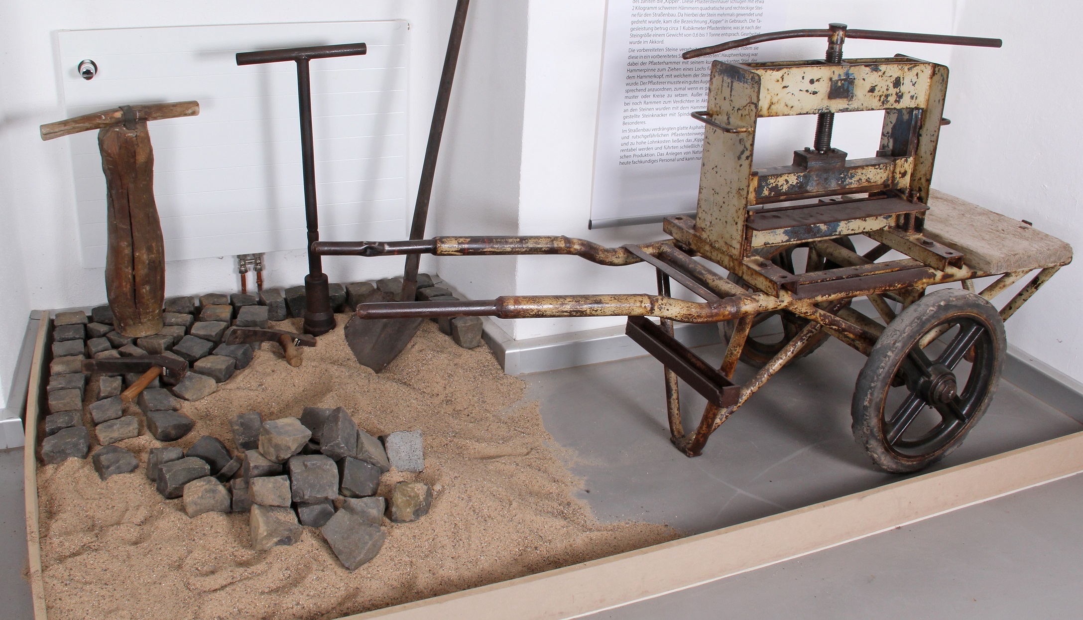 Ein altes Gerät zum Steinbrechen und bearbeitete Pflastersteine sind in der Museumsausstellung.