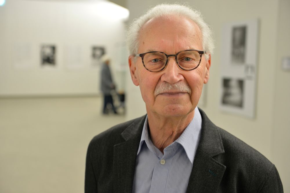 Ein Herr mit weißen Haaren und Brille schaut in die Kamera.