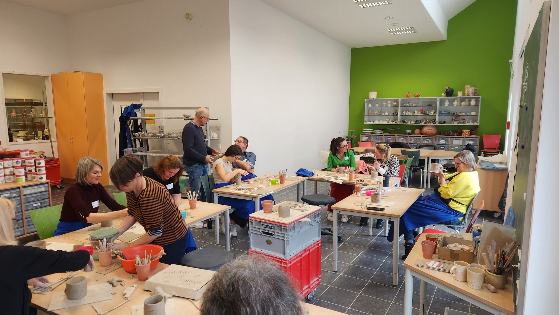 In der Keramikwerkstatt arbeiten Frauen und Männer an Tischen mit Ton.