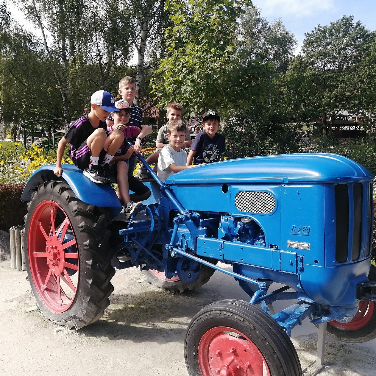 Mehrere Kinder sitzen auf einem großen blauen Traktor