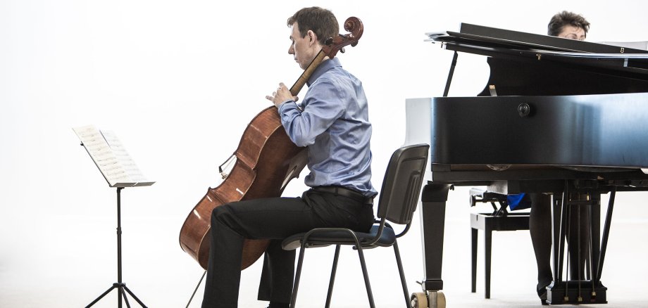 Ein Mann am Kontrabass spielt neben einem Klavier.