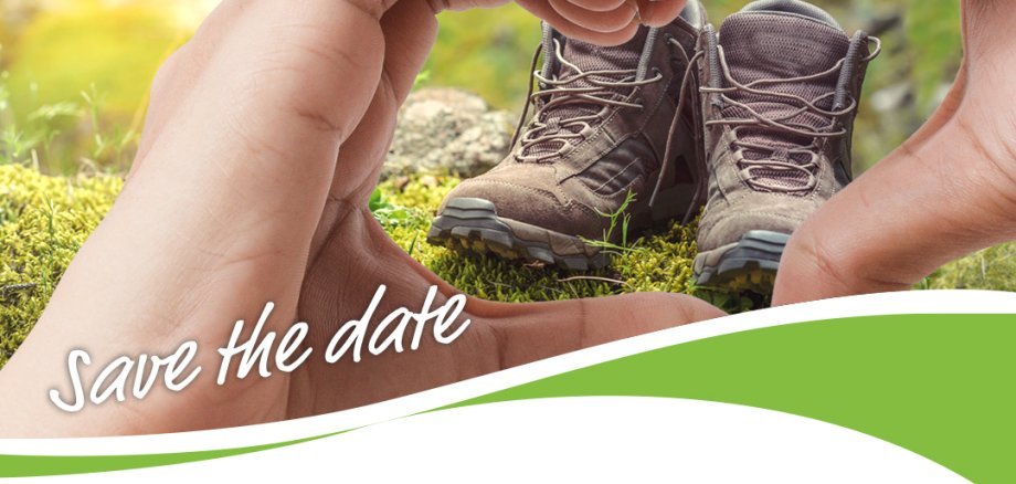 Zwei Hände formen ein Herz durch das zwei Wanderschuhe zu sehen sind.