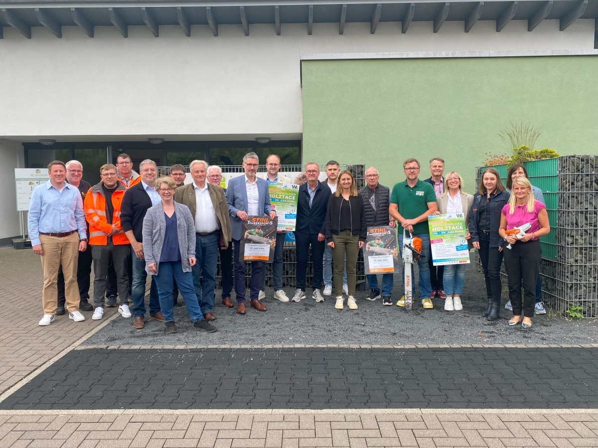 Viele Frauen und Männer stehen vor einem Gebäude, zum Teil mit Plakaten der Holztage und von Stihl in der Hand.