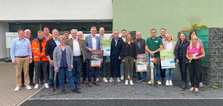 Viele Frauen und Männer stehen vor einem Gebäude, zum Teil mit Plakaten der Holztage und von Stihl in der Hand.