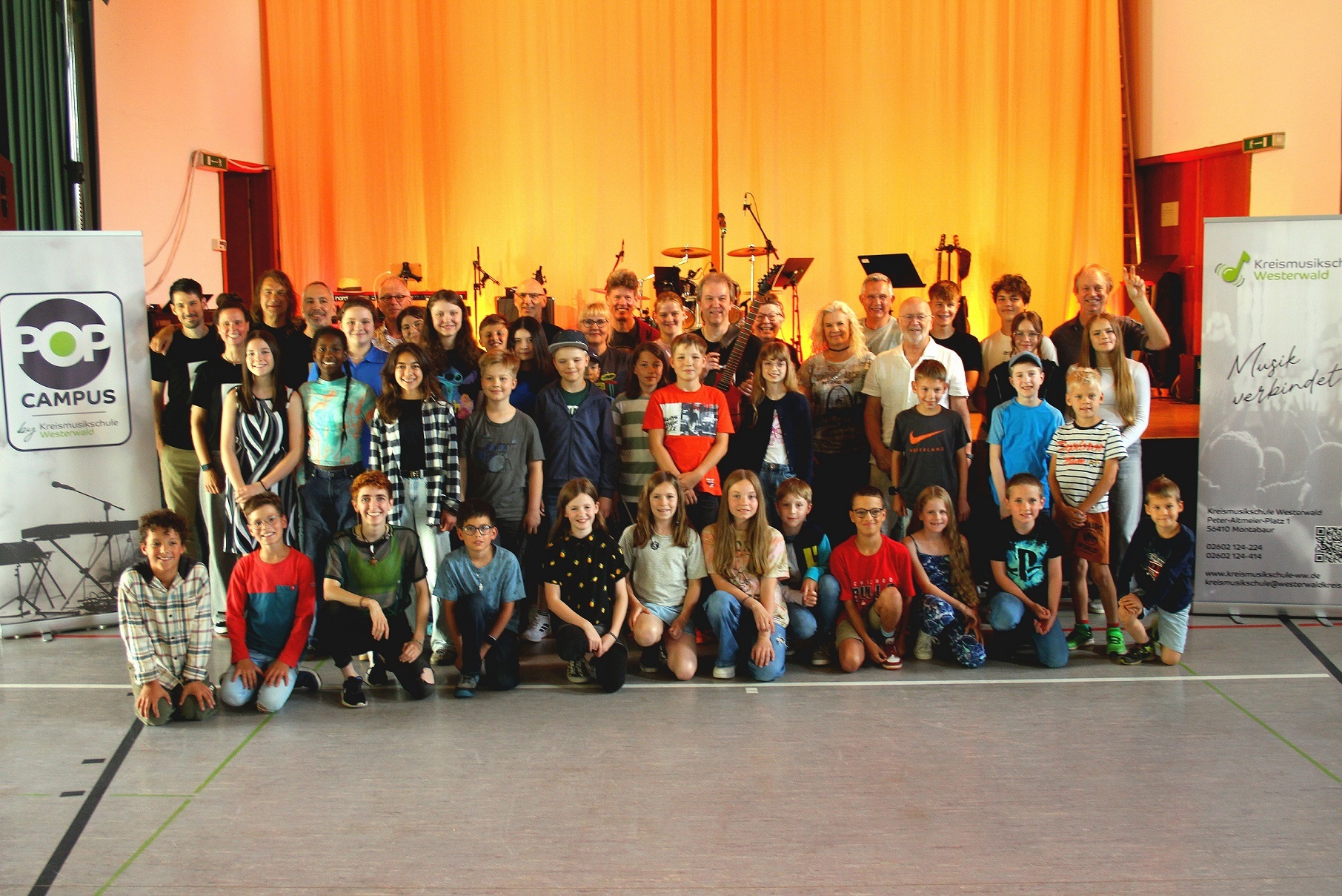 Eine große Gruppe Erwachsener und Kinder steht vor Instrumenten in der Turnhalle.
