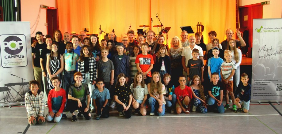 Eine große Gruppe Erwachsener und Kinder steht vor Instrumenten in der Turnhalle.