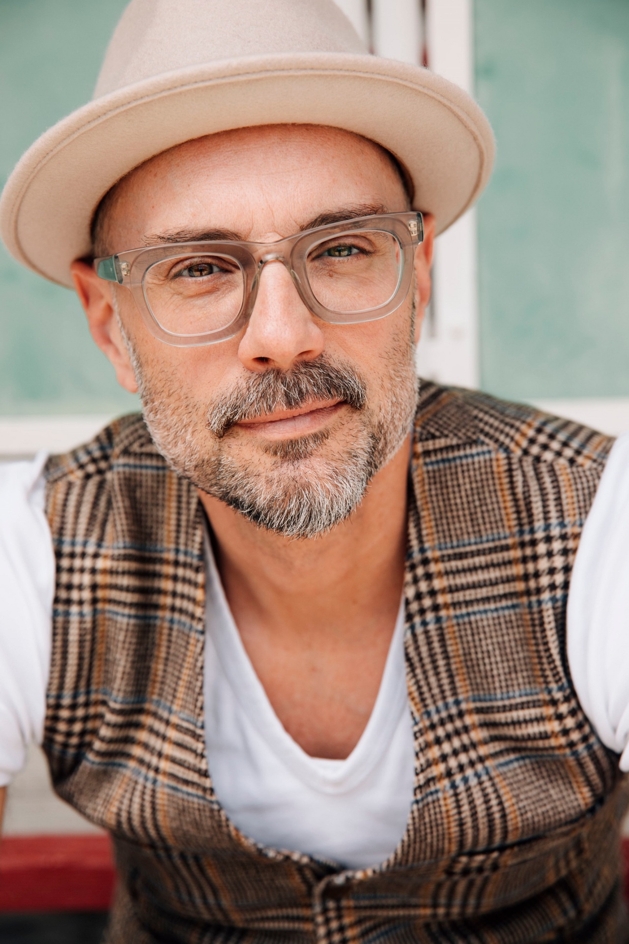 In dem Porträt ist ein bärtiger Mann mit Brille und Hut sowie karierter Weste zu sehen.