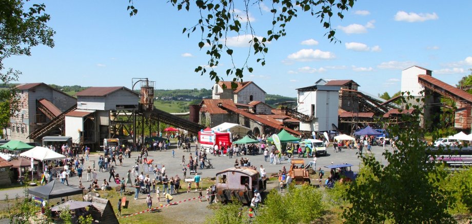 Von einem Hügel aus ist das Gelände des Parks mit seinen Industrieanlagen, dazwischen Hüpfburgen und Besucher sichtbar.