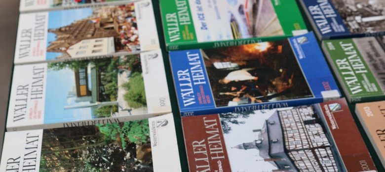 Die 40 Ausgaben der Wäller Heimat liegen auf einem Tisch in mehreren Reihen nebeneinander.