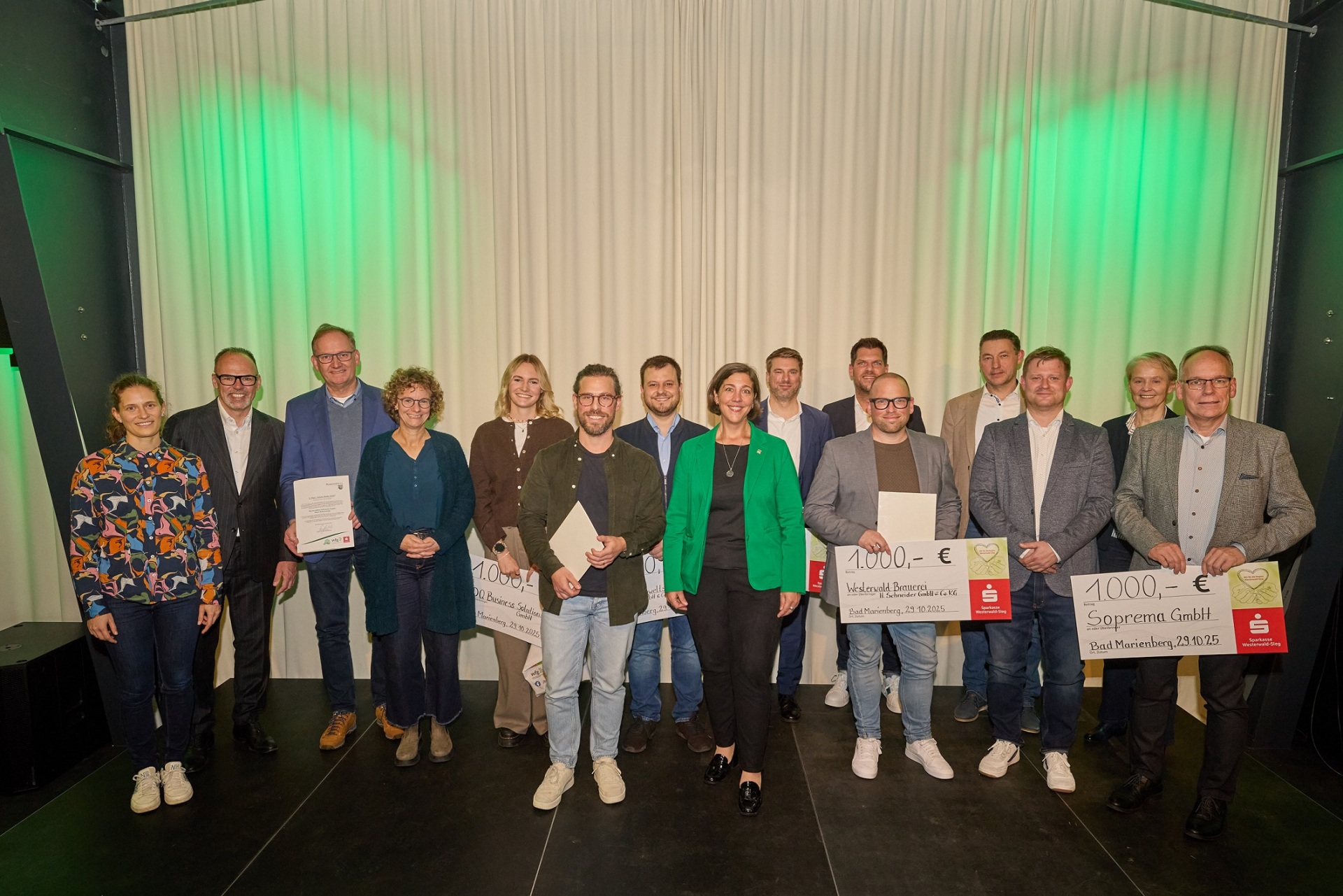 Frauen und Männer stehen auf einer Bühne und einige halten große Schecks über jeweils 1.000 Euro in den Händen.