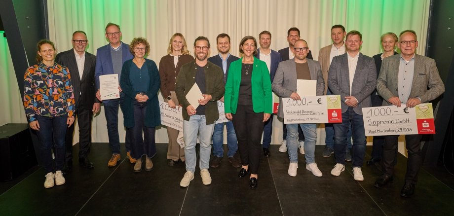 Frauen und Männer stehen auf einer Bühne und einige halten große Schecks über jeweils 1.000 Euro in den Händen.