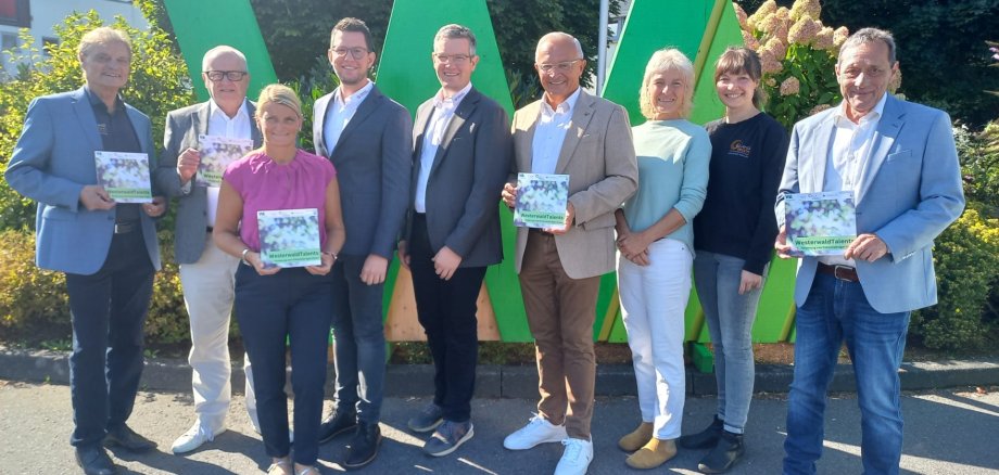 Mehrere Frauen und Männer stehen vor einem großen grünen W mit einem Flyer von WesterwaldTalents in der Hand.