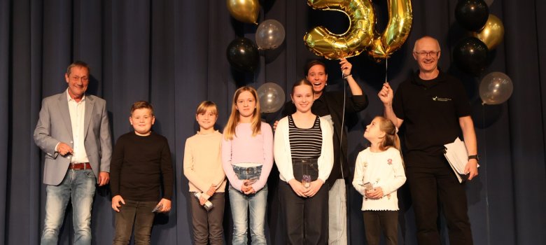 Alle Genannten stehen auf der Bühne und halten Folienballons mit der Zahl 50.