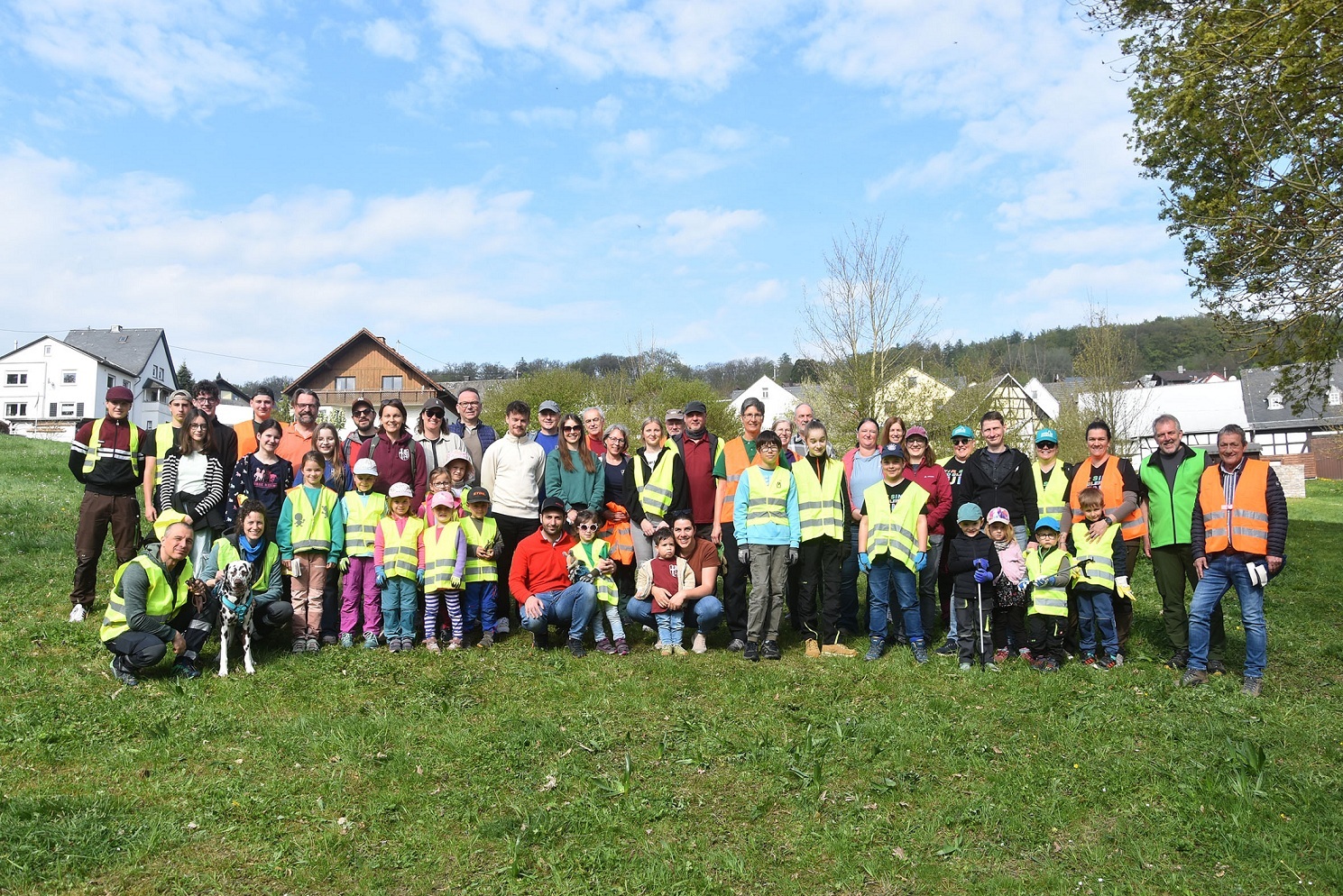 Zahlreiche Erwachsene und Kinder in Warnwesten stehen auf einer Wiese.