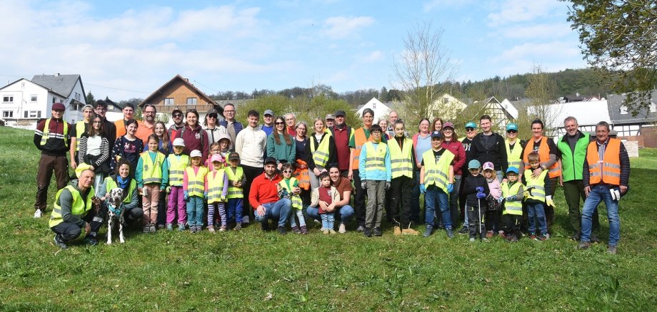 Zahlreiche Erwachsene und Kinder in Warnwesten stehen auf einer Wiese.