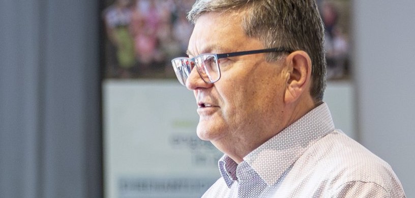 Ein Mann mit Brille im fliederfarbenen Hemd