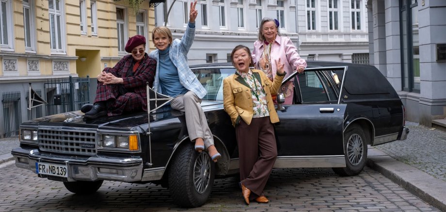 Vier Seniorinnen befinden sich an einem großen Auto.