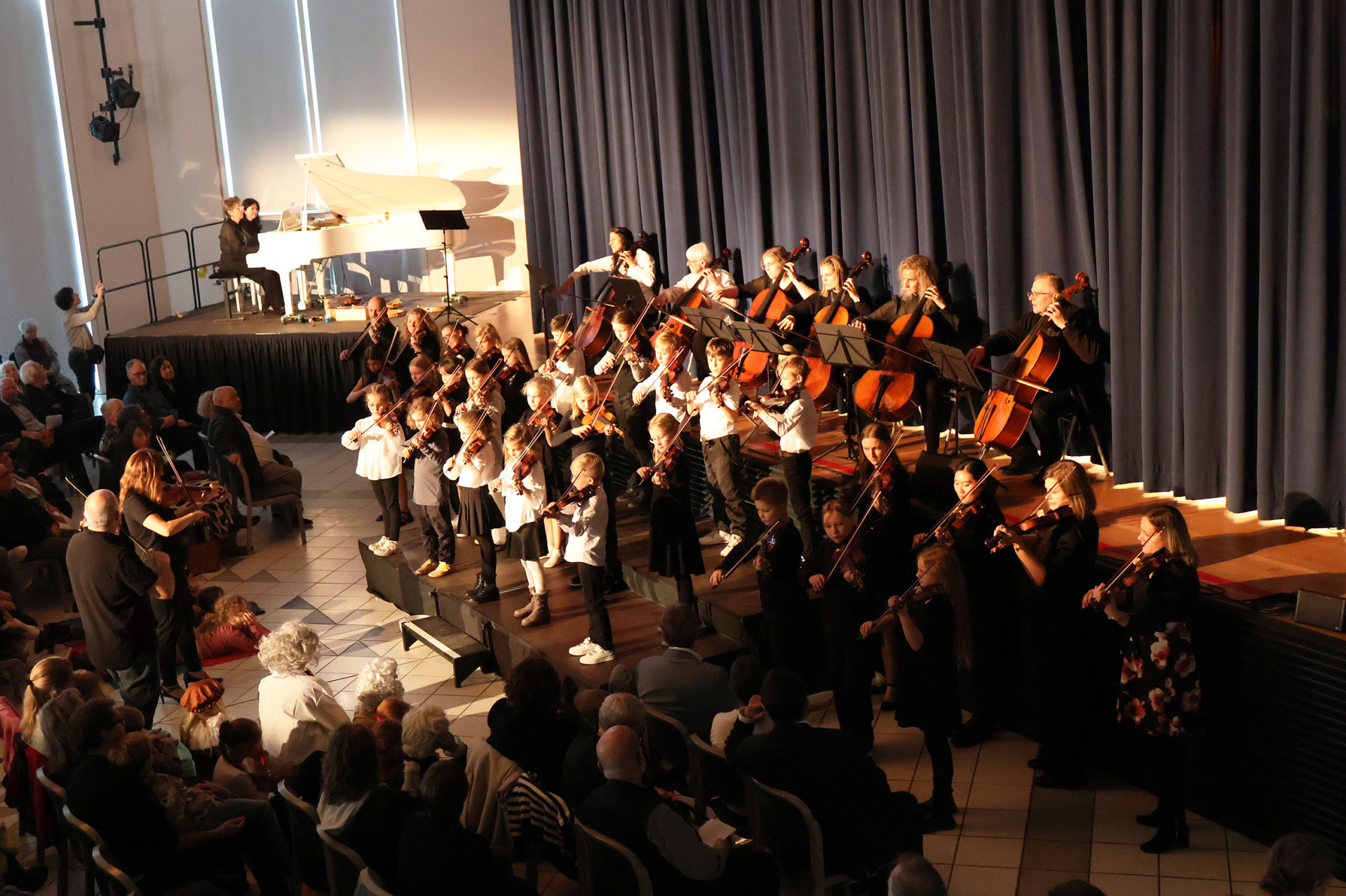 Auf einer Bühne sitzen Musiker mit Streichinstrumenten.