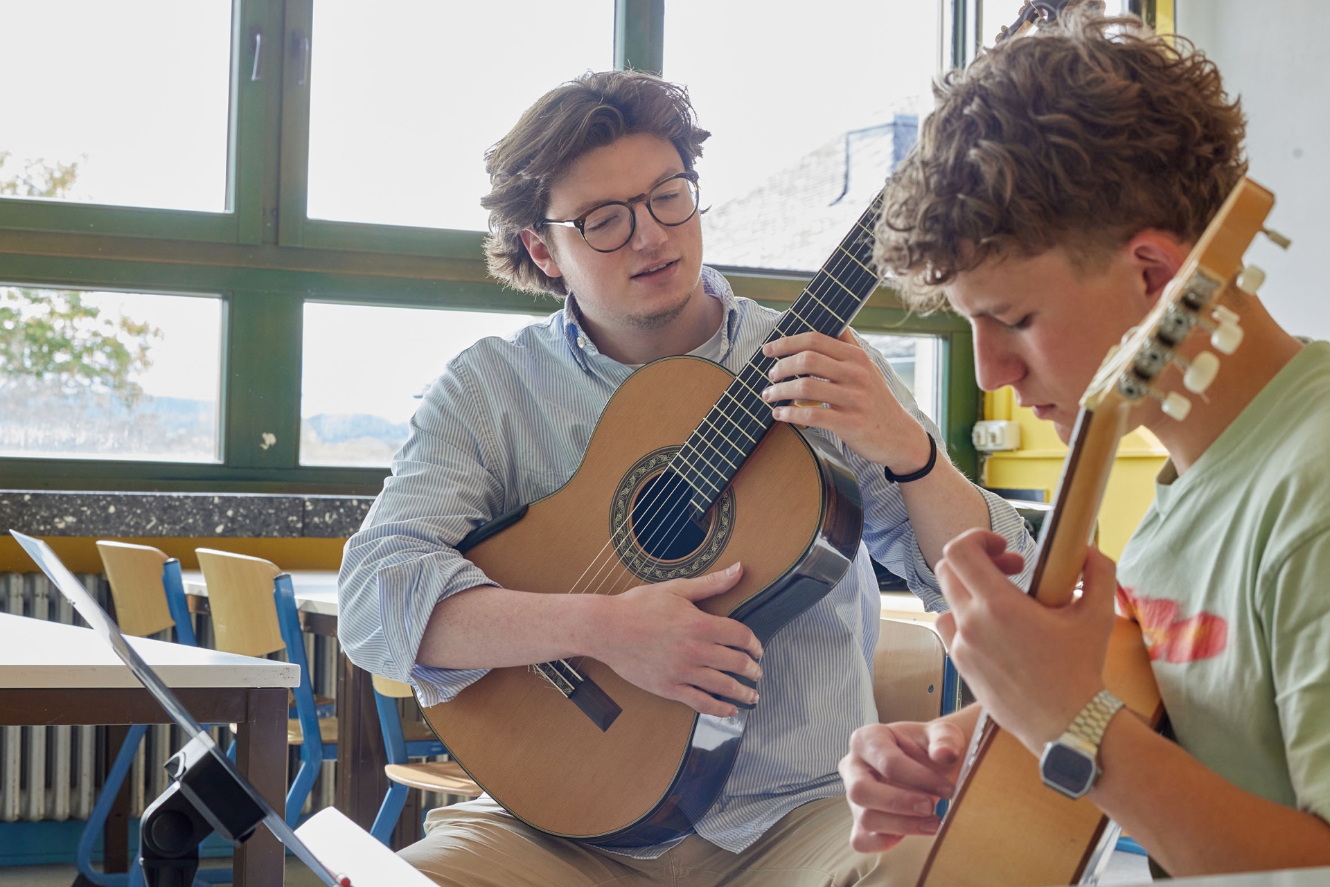 2 junge Männer spielen Girarre.