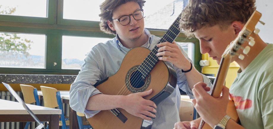2 junge Männer spielen Girarre.